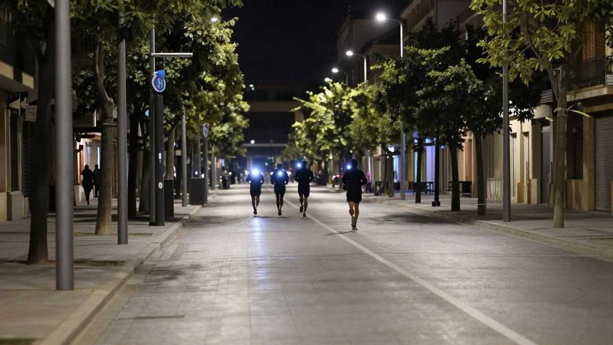 Imagen ilustrativa: avenida urbana iluminada de noche con algunos corredores de fondo difuminados