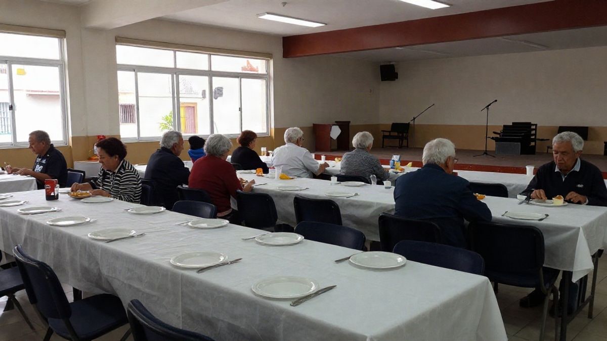 Imagen ilustrativa: interior de un salón comunitario con mesas preparadas para una comida y un escenario con micrófono