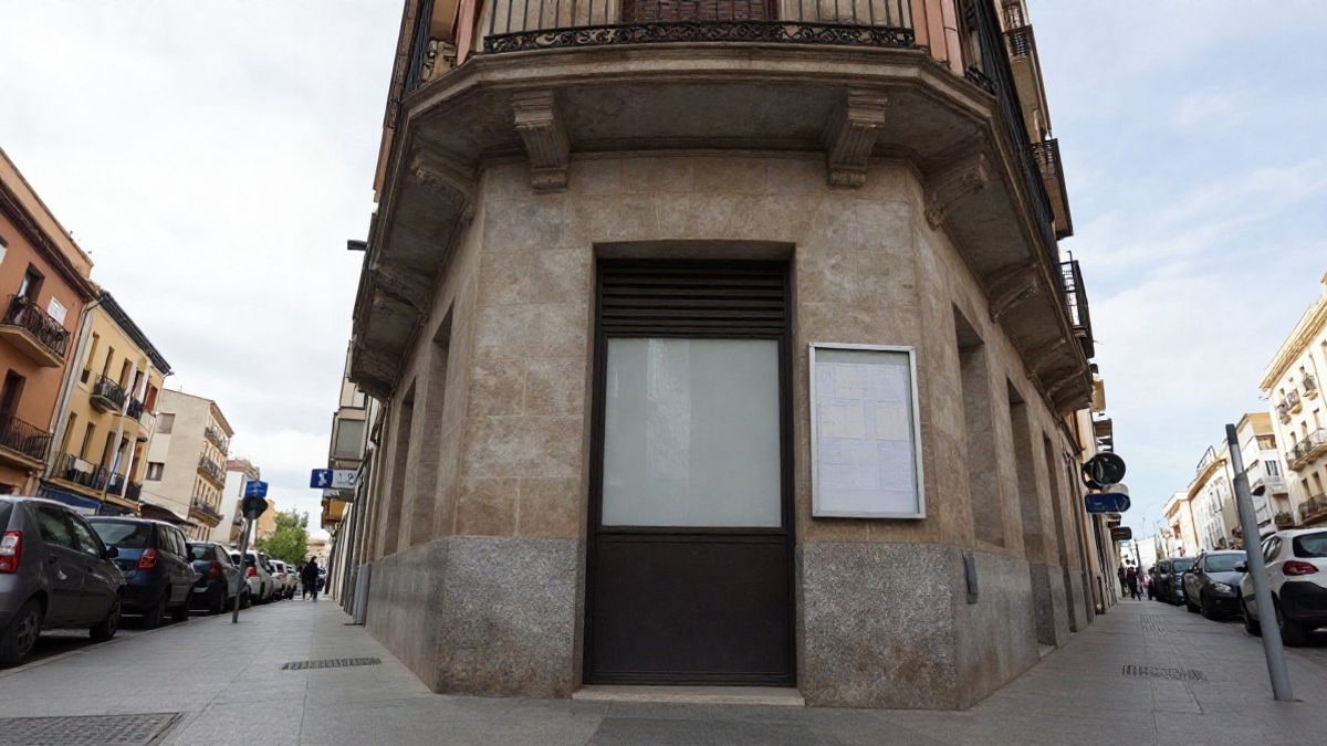 Imagen ilustrativa: ángulo bajo de la fachada de un edificio municipal genérico con tablón de anuncios vacío en la calle