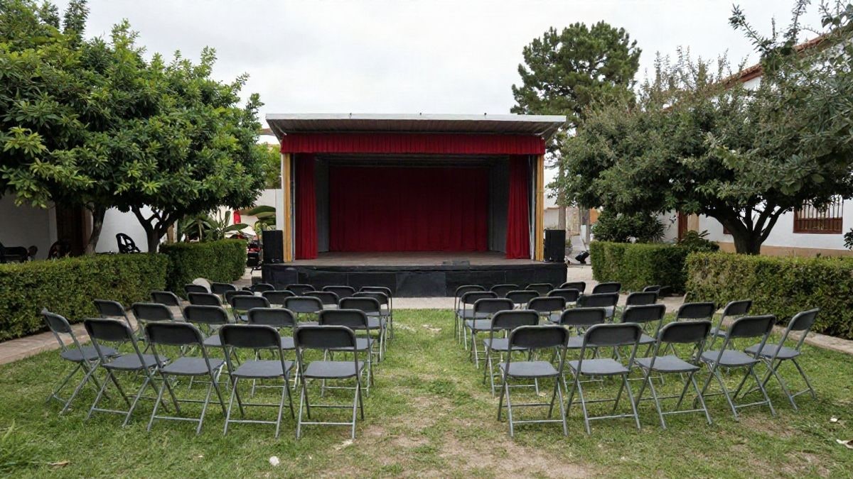 Imagen ilustrativa: jardines con sillas plegables y un pequeño escenario al aire libre, preparados para una función teatral