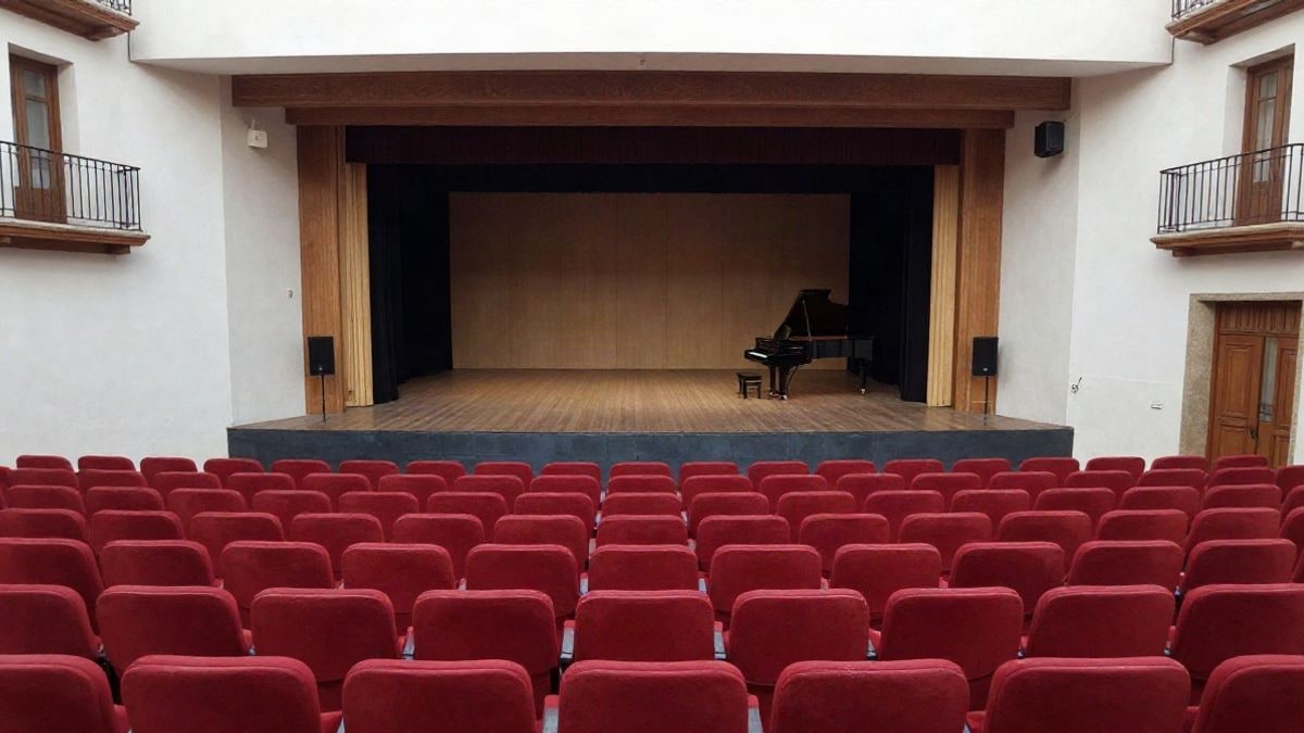Illustrative image: empty stage of a municipal theatre with red seats and a grand piano