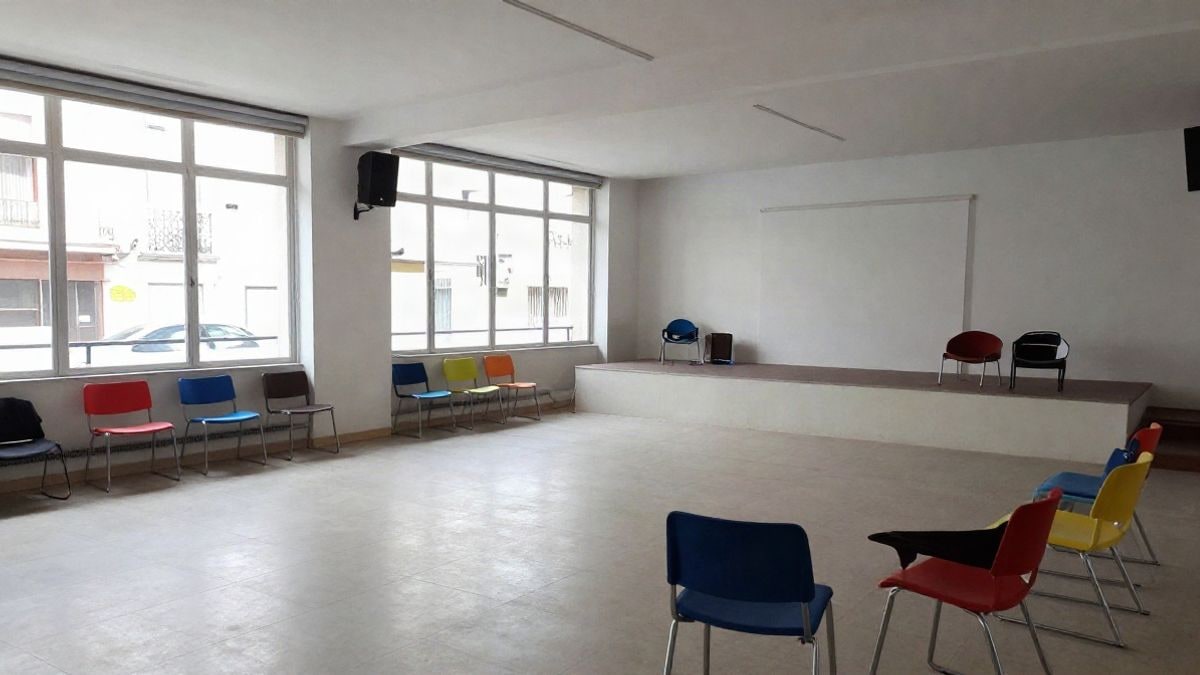 Imagen ilustrativa: sala común vacía de un centro juvenil con sillas de colores y ventanales luminosos.