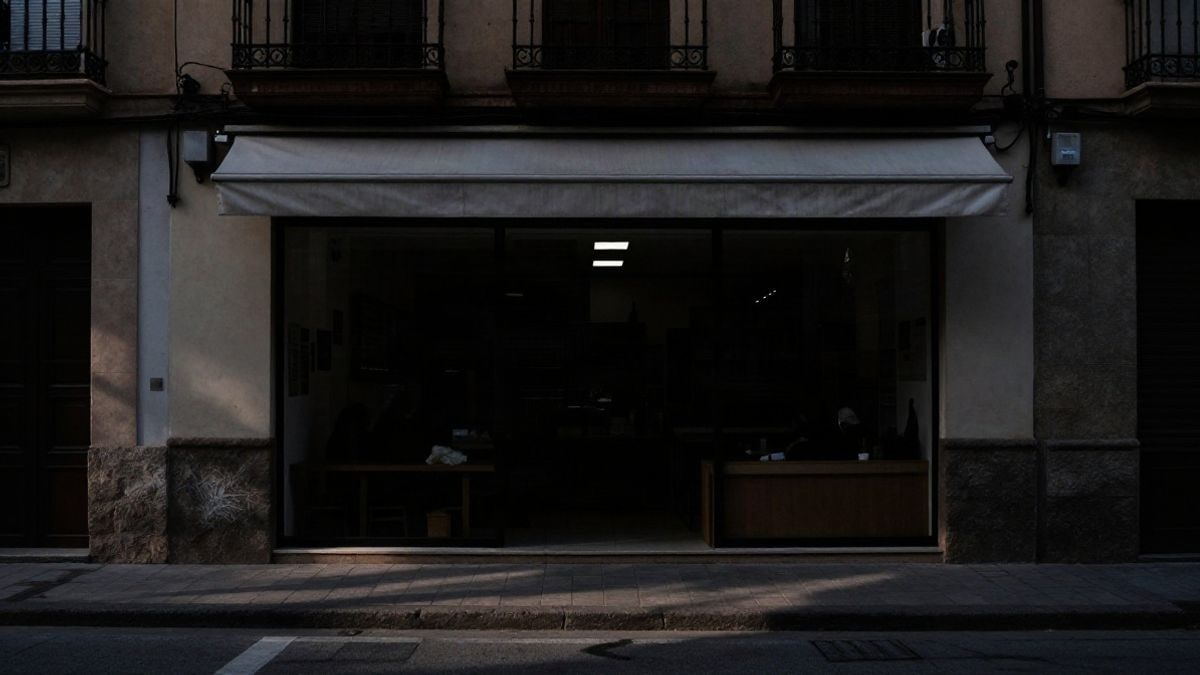 Imagen ilustrativa: fachada de un pequeño comercio en una calle con sombras al atardecer