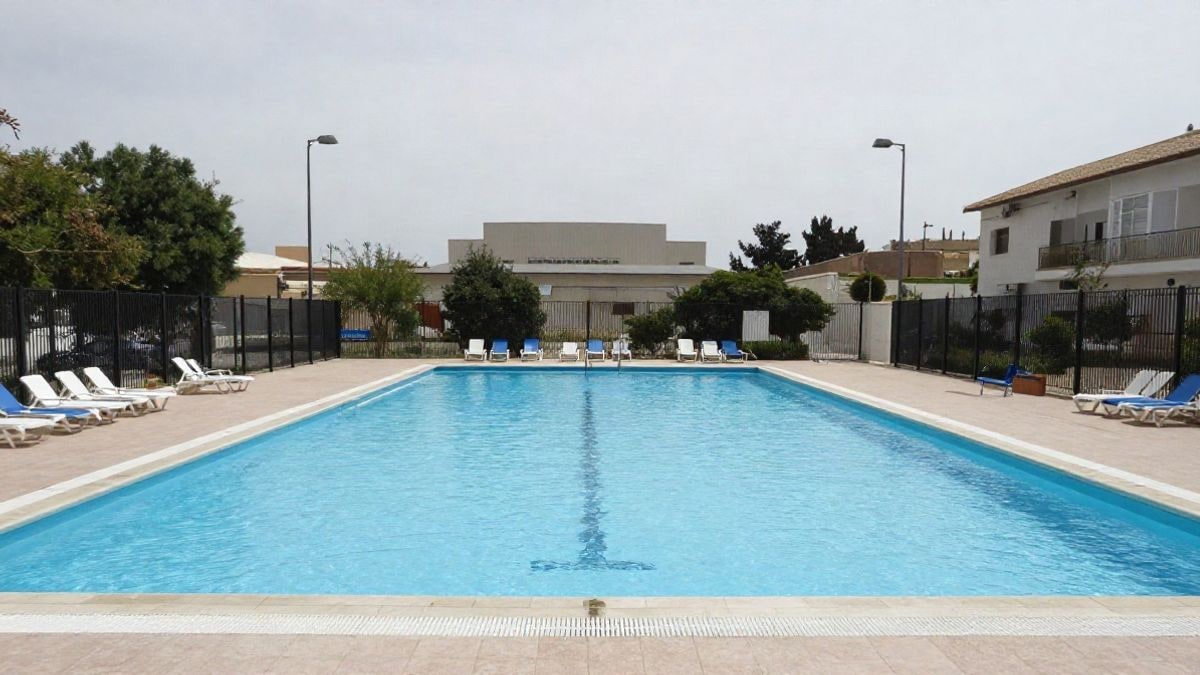 Imagen ilustrativa: piscina municipal al aire libre con agua cristalina y tumbonas vacías.