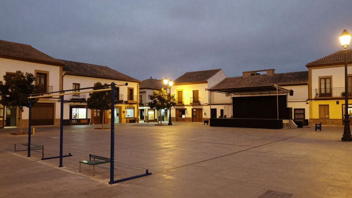 Imagen ilustrativa: plaza pública española de noche con stands y escenario de actividades deportivas