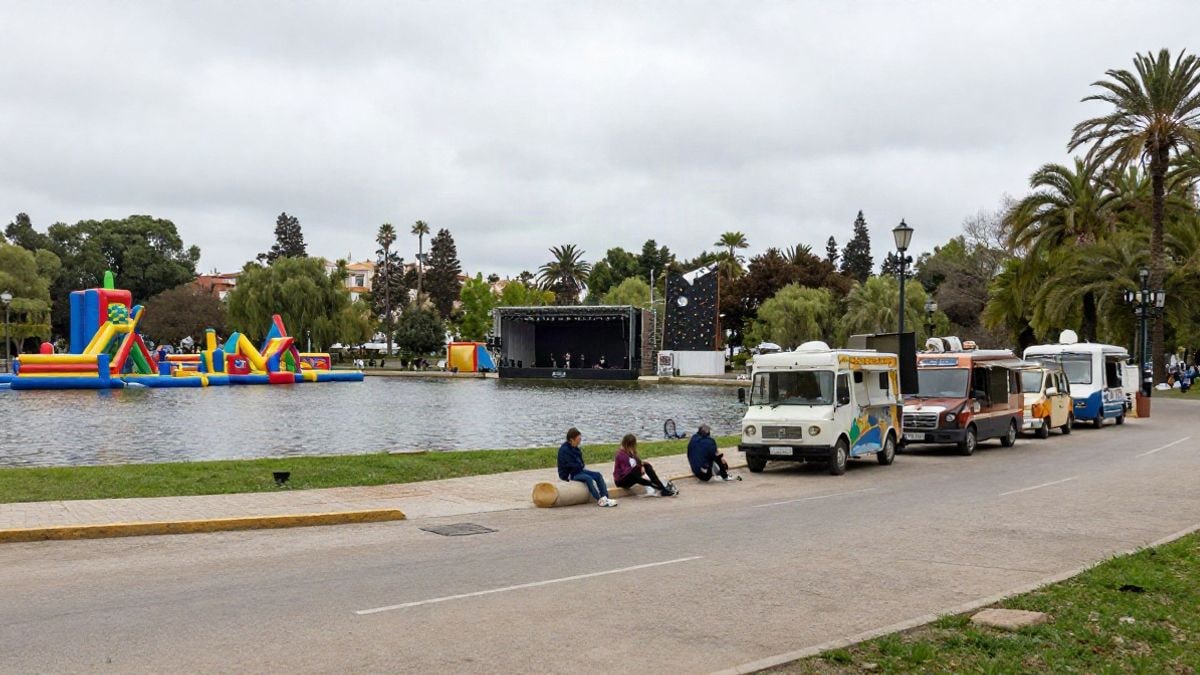 Imagen ilustrativa: un parque con un lago, un escenario lejano, hinchables y foodtrucks en un día nublado