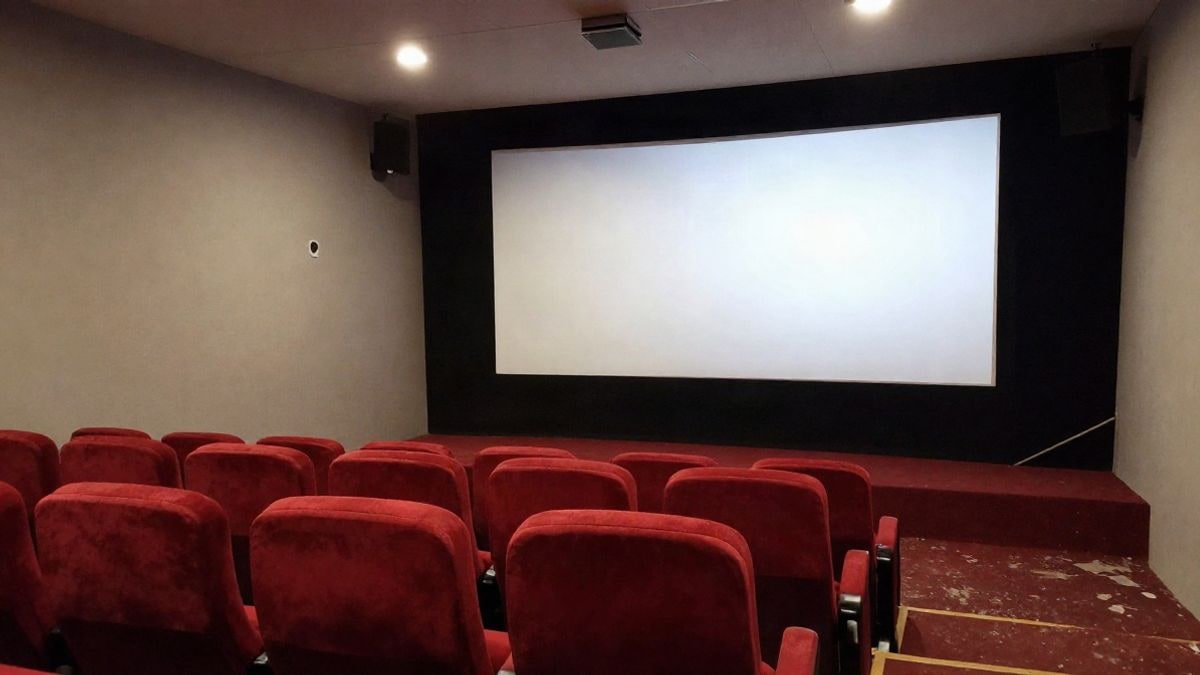 Imagen ilustrativa: sala de cine vacía con butacas rojas y pantalla en blanco, con el haz del proyector.