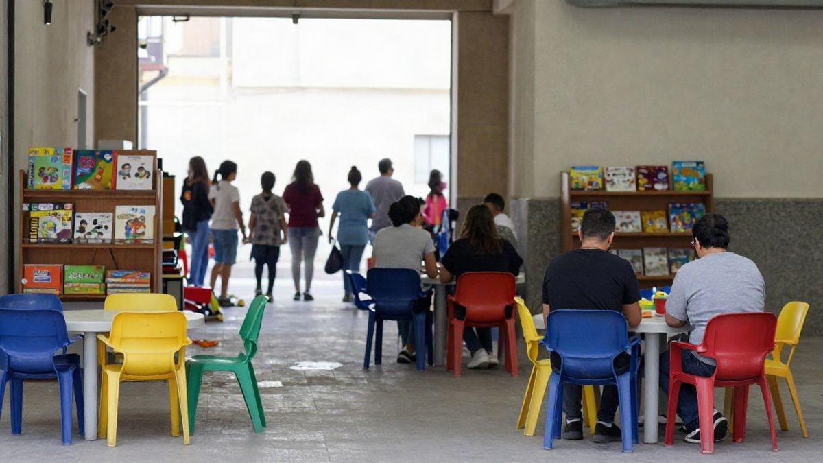 Imagen ilustrativa: una sala de ludoteca con mesas, sillas de colores y estanterías con juegos y libros, sin personas.