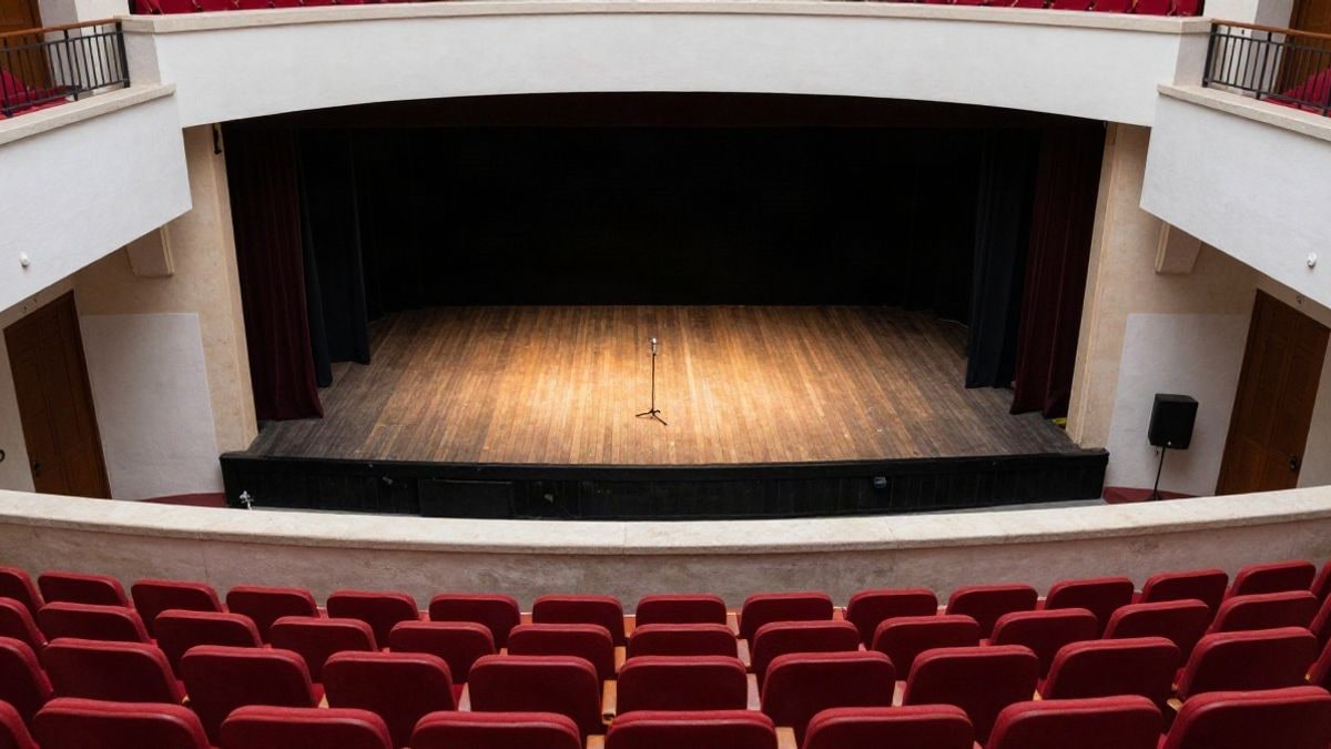 Imagen ilustrativa: vista cenital de un escenario de teatro vacío con butacas rojas
