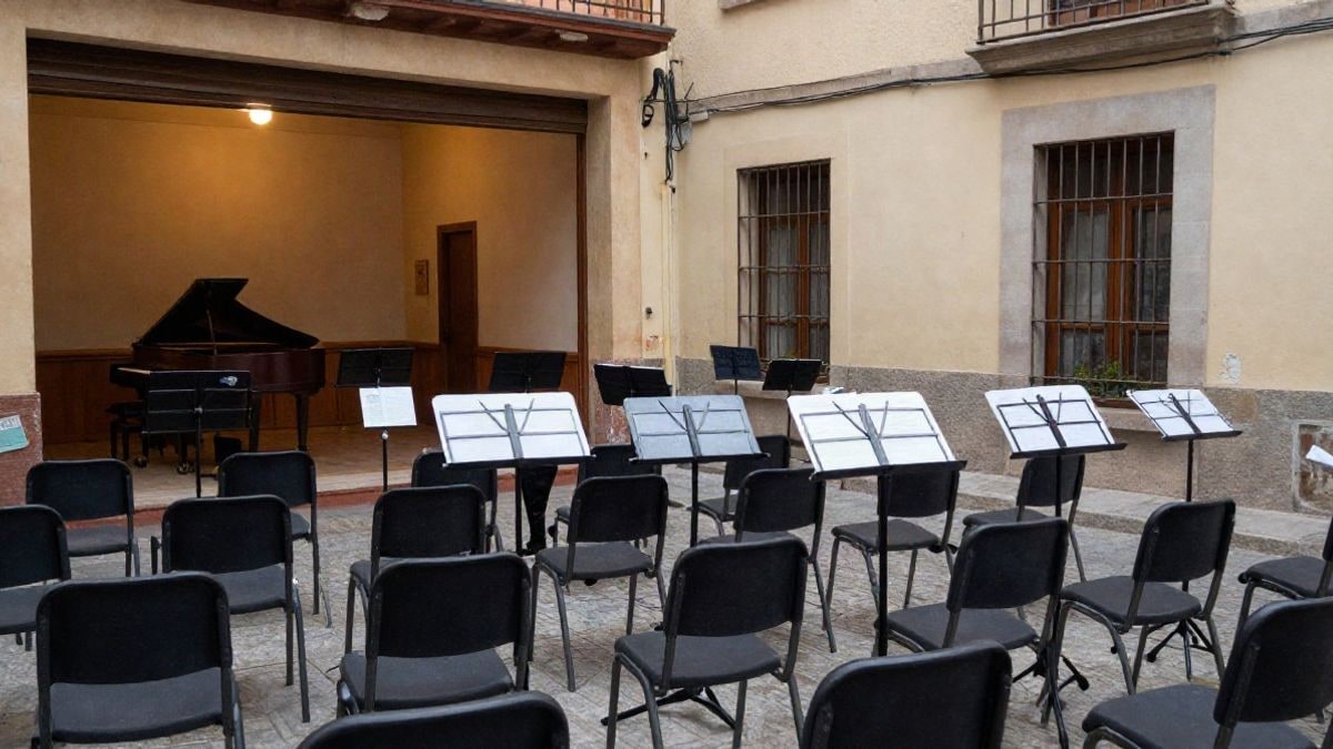 Imagen ilustrativa: sala de ensayo con sillas y atriles vacíos y un piano al fondo