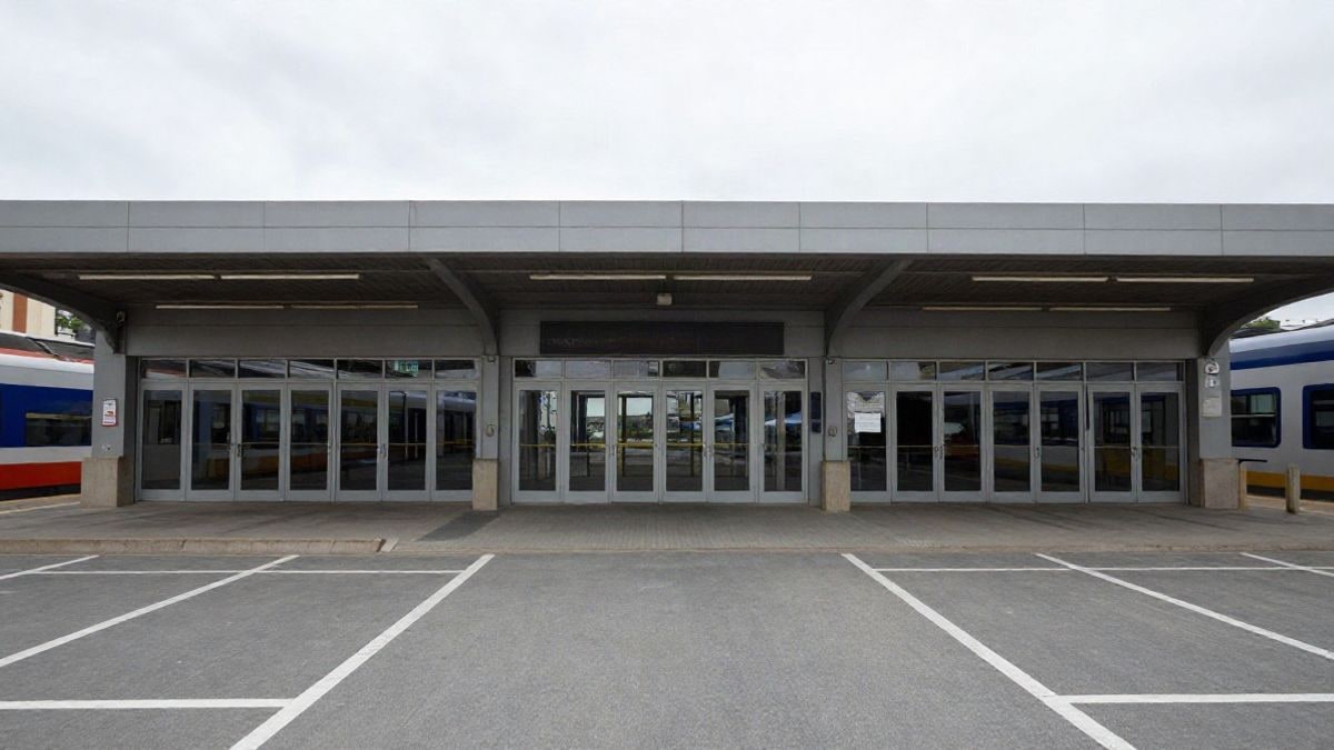 Illustrative image: wide-angle view of a parking lot next to a train station entrance with lines converging towards the doors