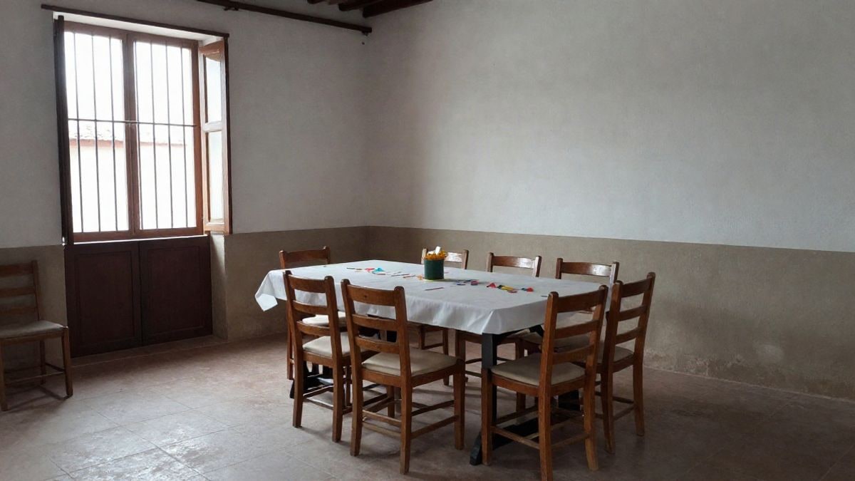 Imagen ilustrativa: interior de un salón de pueblo preparado para una fiesta local con sillas y decoración sencilla