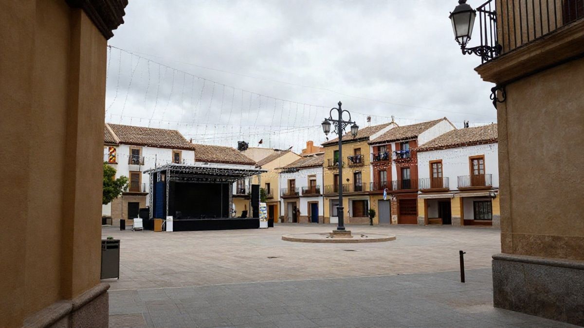 Imagen ilustrativa: plaza de un pueblo español engalanada para unas fiestas patronales, con luces y escenario