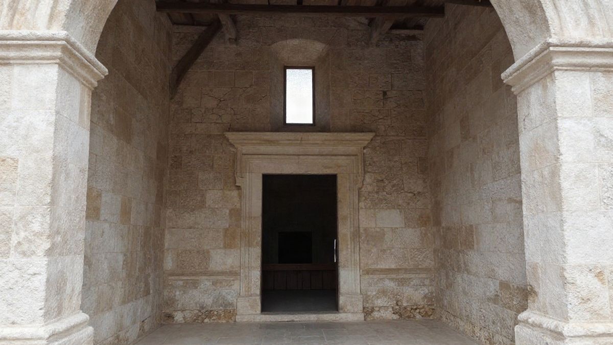 Imagen ilustrativa: interior de una capilla antigua en obras con andamios y grietas sobre una puerta de piedra