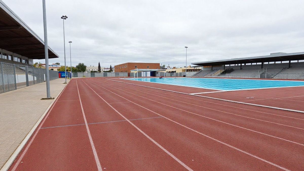 Imagen ilustrativa: instalaciones deportivas municipales con pista y piscina cubierta en un día nublado