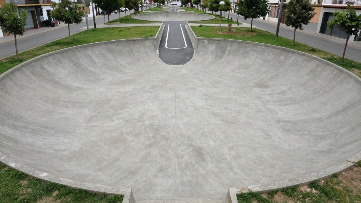 Illustrative image: aerial view of an outdoor skate area with concrete bowls and an asphalt circuit surrounded by grass