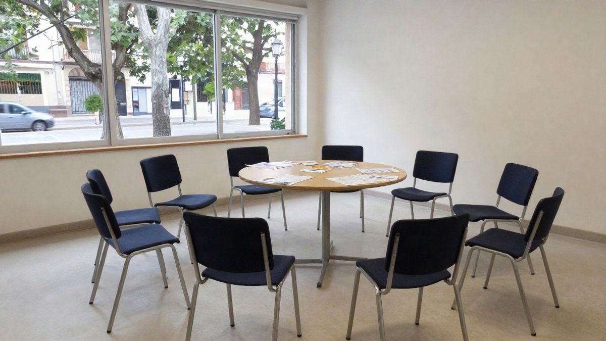 Imagen ilustrativa: una sala comunitaria vacía con sillas en círculo y una mesa con folletos, propia de talleres municipales.