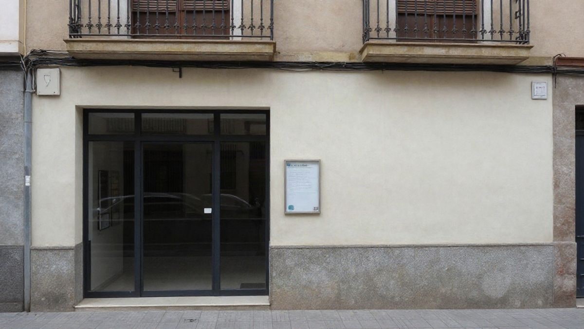 Imagen ilustrativa: fachada lateral de un edificio municipal corriente con una puerta de cristal y un tablón de anuncios