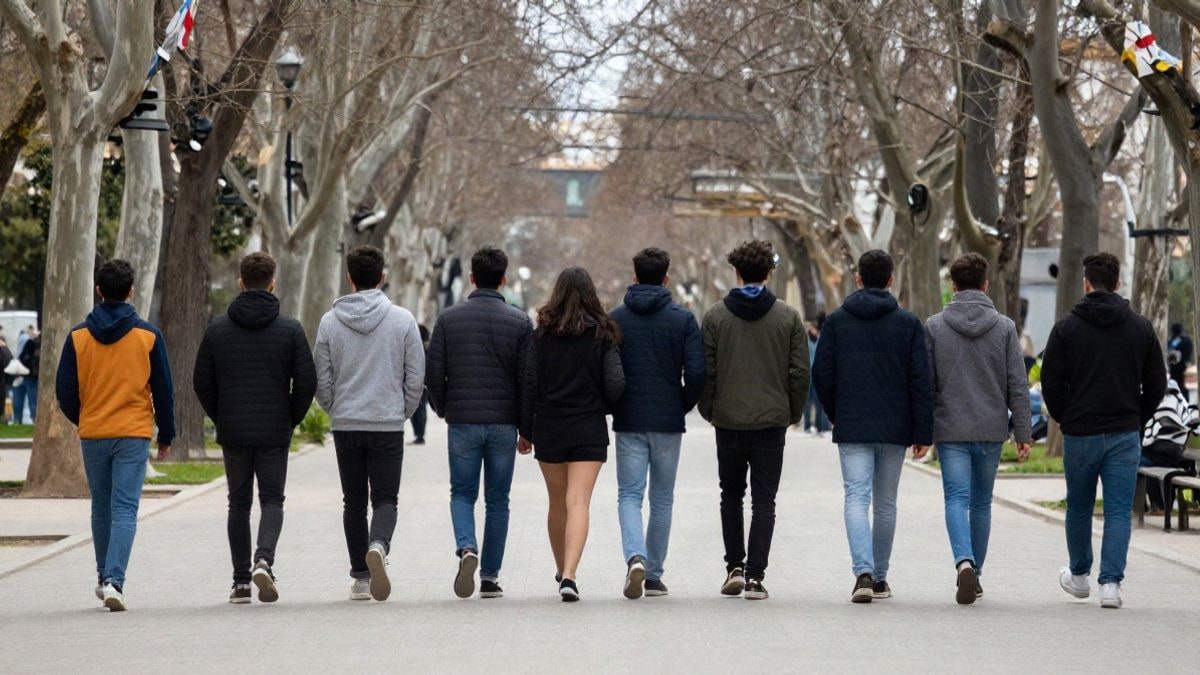 Imagen ilustrativa: un grupo de jóvenes caminando de espaldas por un parque urbano en un día nublado.