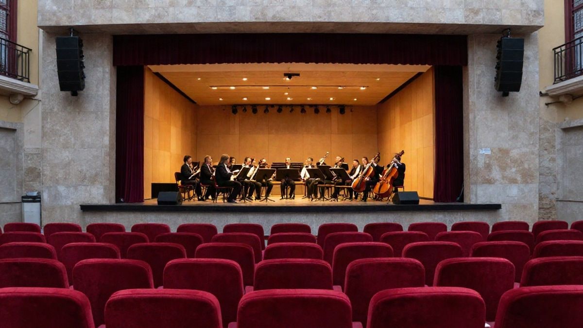 Imagen ilustrativa: interior de un auditorio con escenario iluminado y butacas vacías.