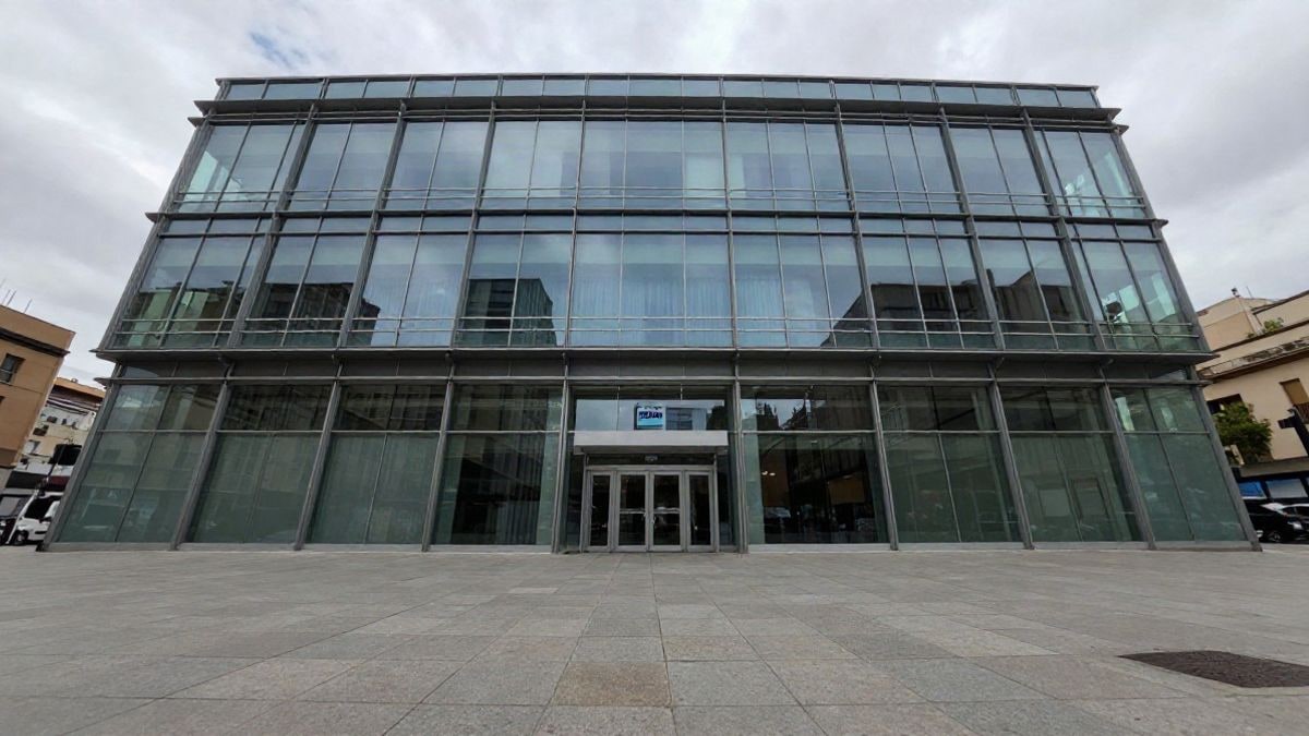 Illustrative image: facade of a modern office building with a cloudy sky in the background