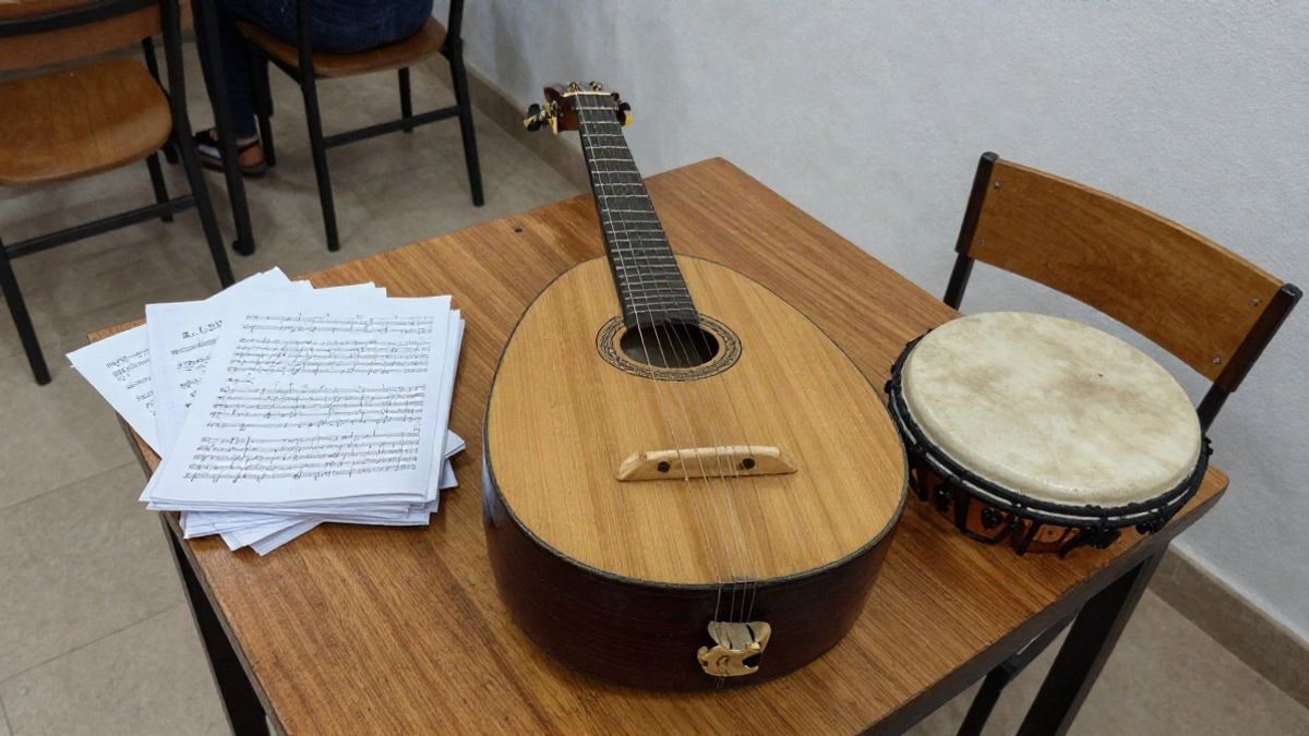 Imagen ilustrativa: vista cenital de un instrumento de cuerda tradicional sobre una mesa de madera junto a partituras