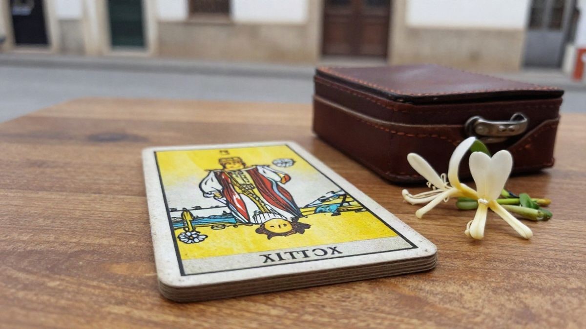 Imagen ilustrativa: primer plano de una baraja de tarot antigua y un maletín de pintor sobre una mesa de madera