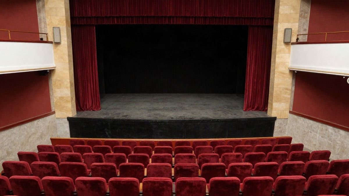 Imagen ilustrativa: vista cenital de un patio de butacas vacío con cortina roja en un teatro