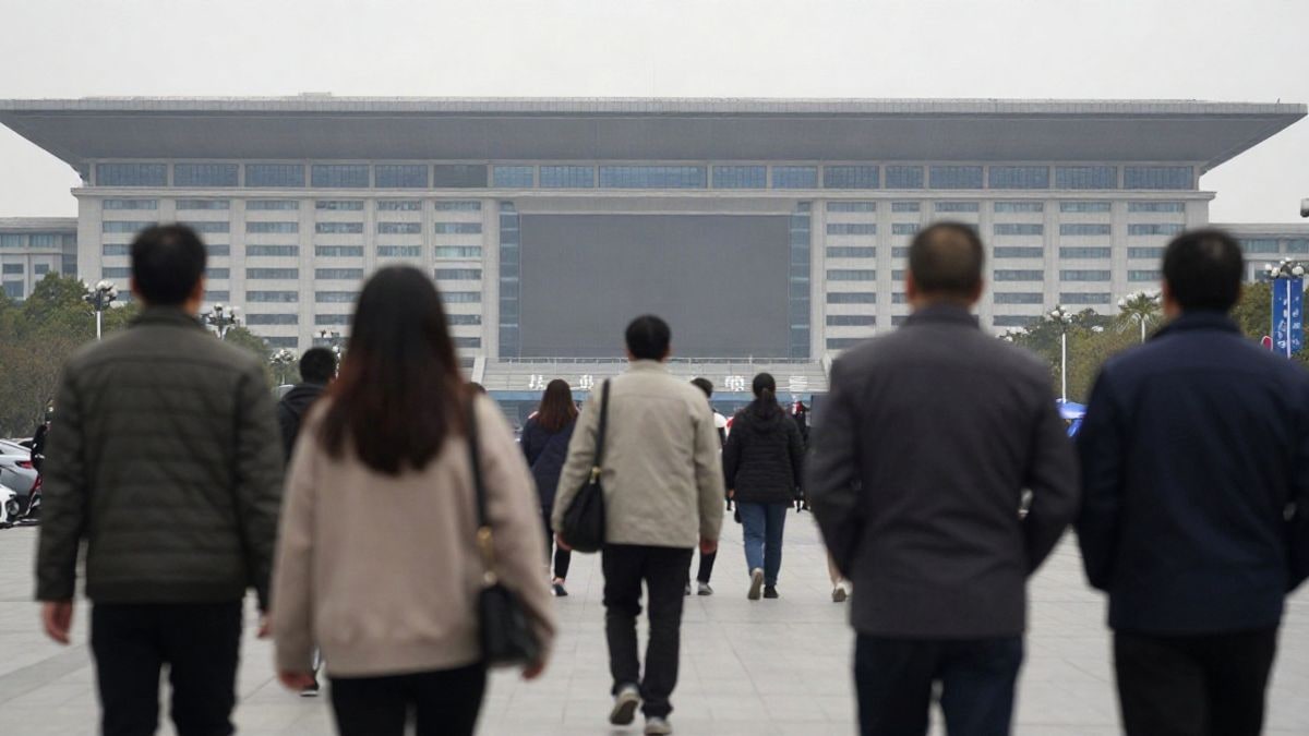 Imagen ilustrativa: un grupo de personas de espaldas en una plaza urbana de China junto a un centro de convenciones.
