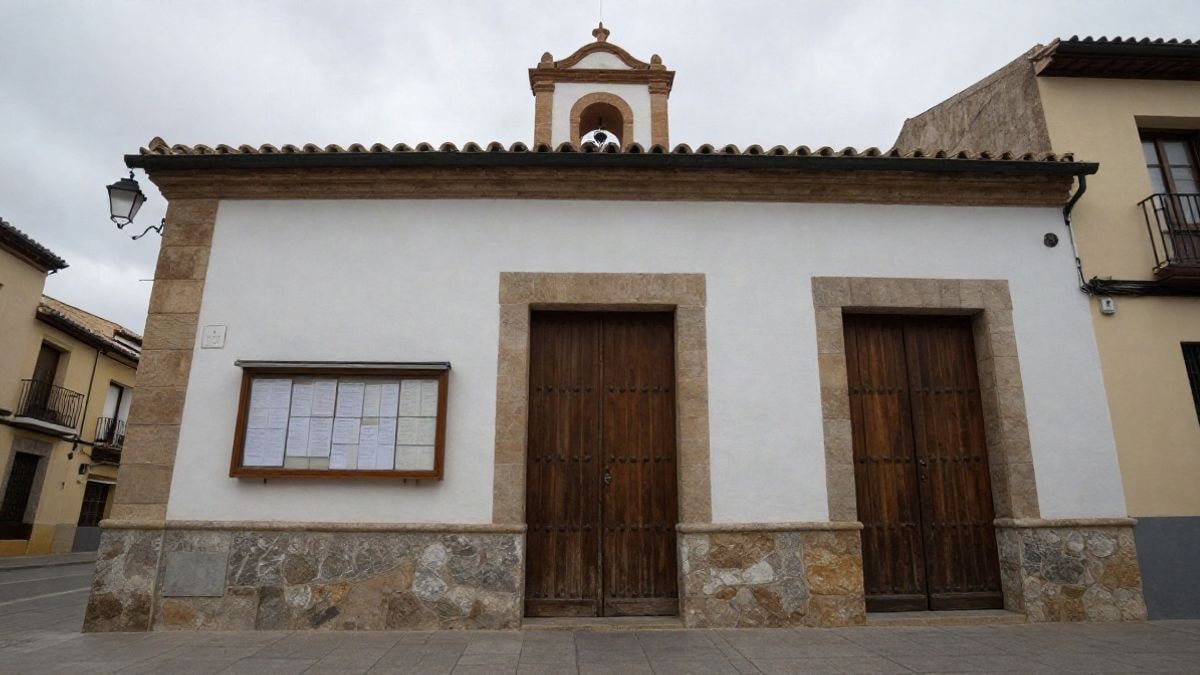Imagen ilustrativa: fachada genérica de un edificio consistorial con tablón de anuncios en un día nublado