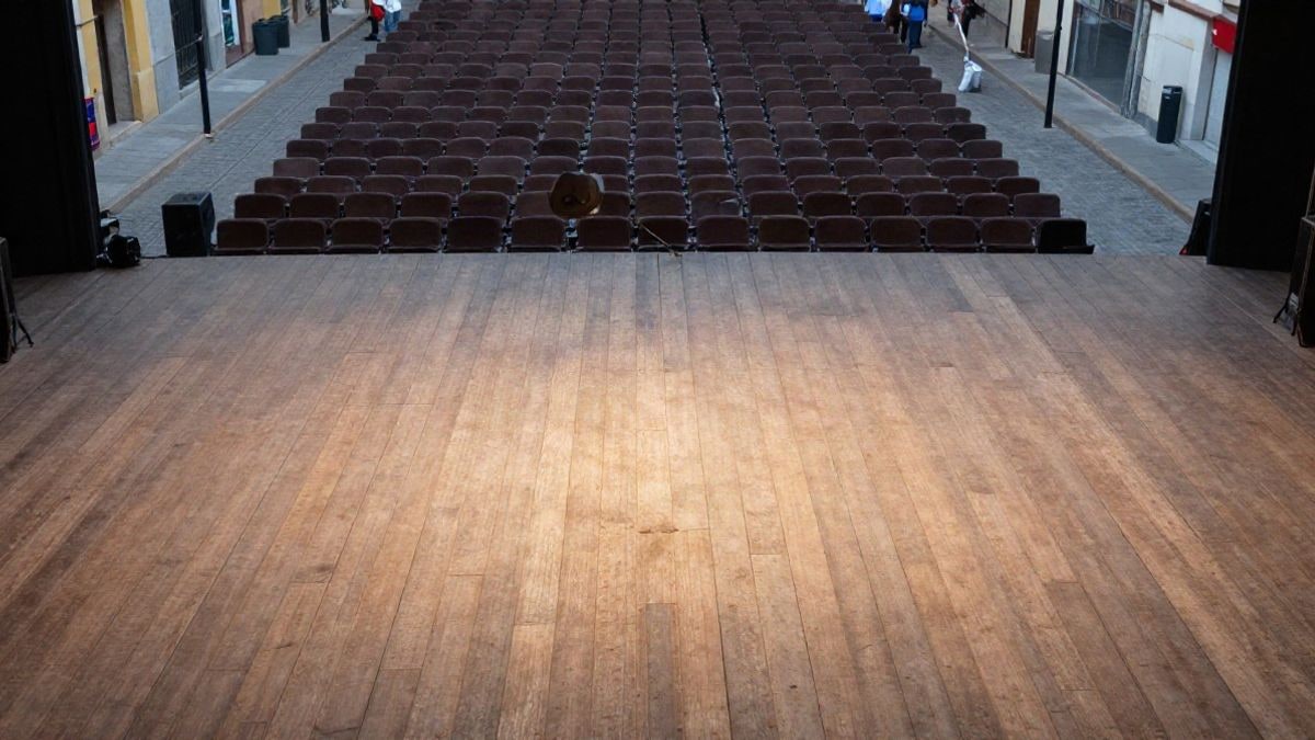 Illustrative image: overhead view of an empty theatre stage with lights and seats in the background