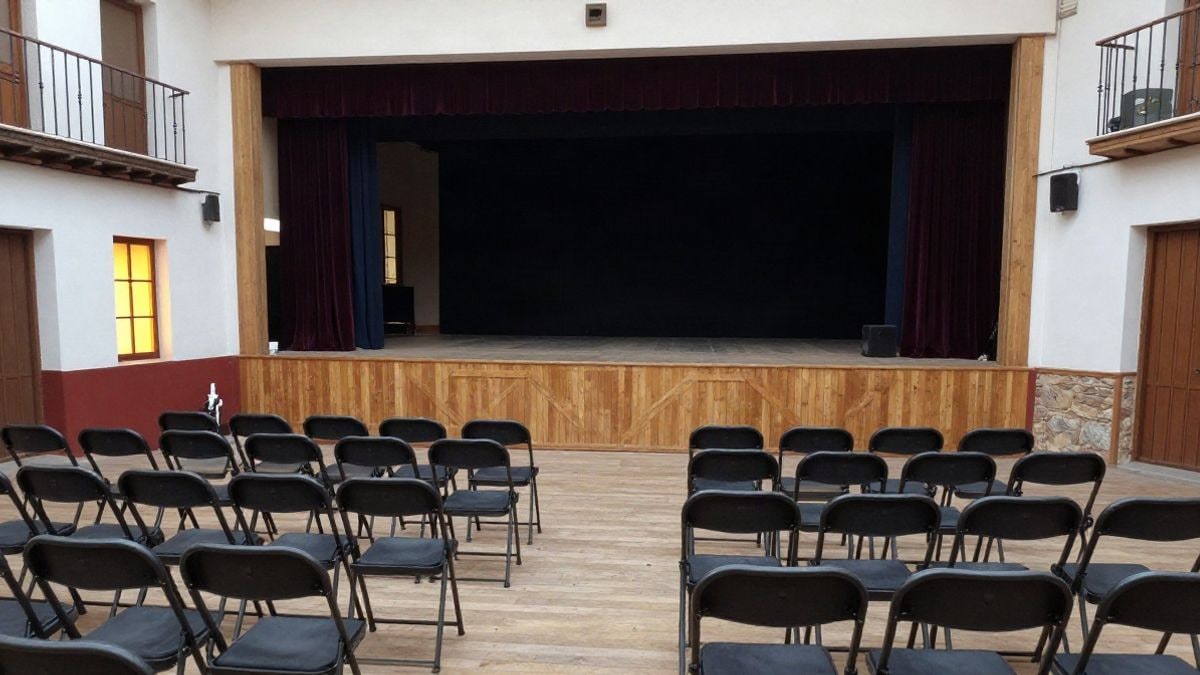 Illustrative image: interior of a multipurpose classroom with empty chairs in front of a small stage with curtains