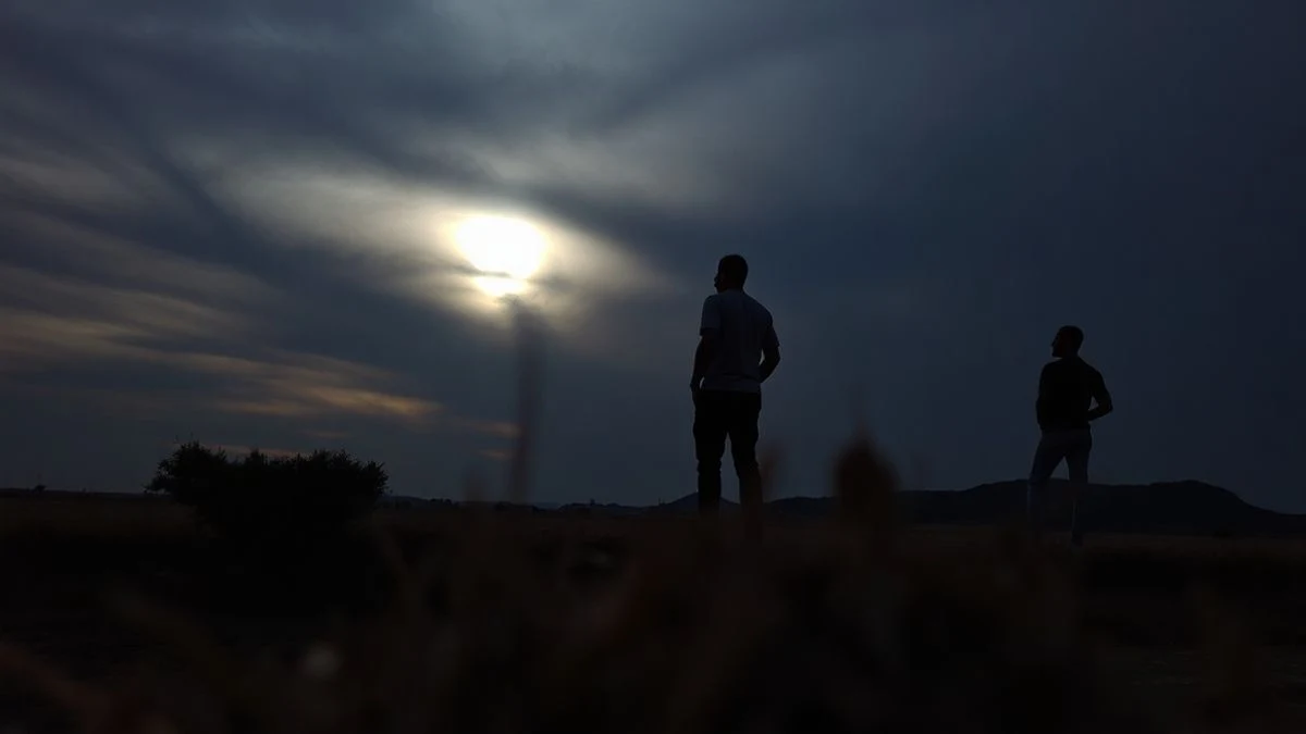 Illustrative image: rural landscape at sunset with the sky darkened by a solar eclipse and silhouettes of trees in the foreground.
