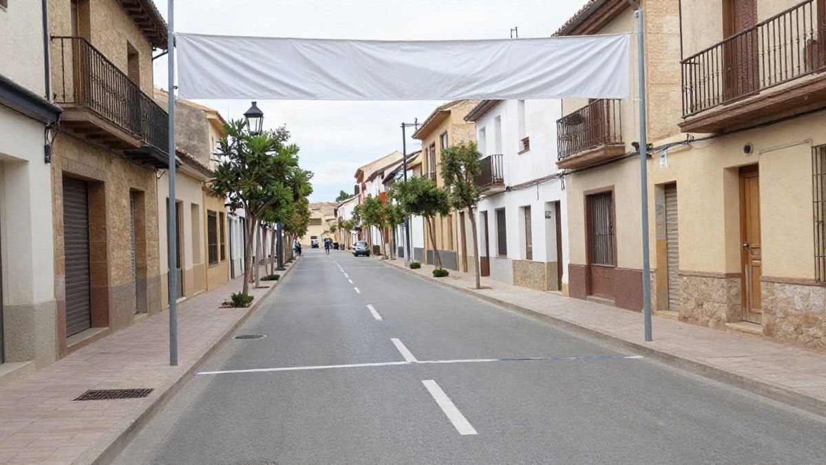Imagen ilustrativa: calle de un pueblo con línea de salida de una carrera popular, con arco hinchable y edificios al fondo.