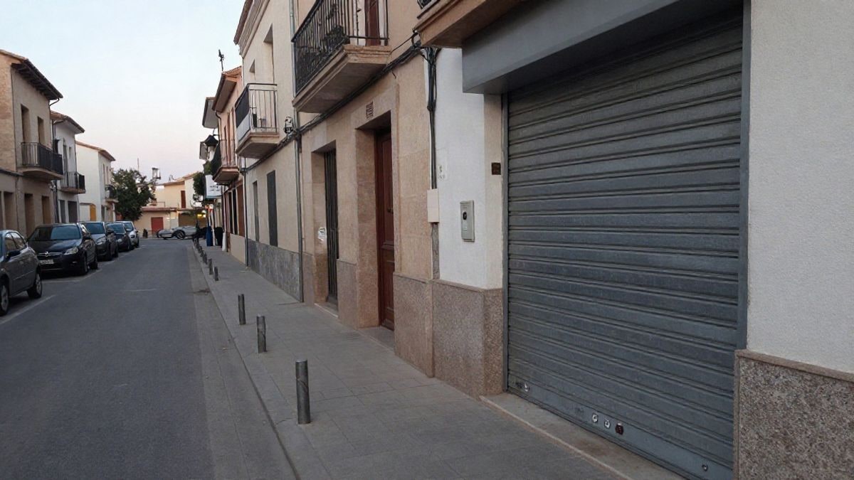 Imagen ilustrativa: persiana metálica de un comercio con pivote de acero en una calle española corriente