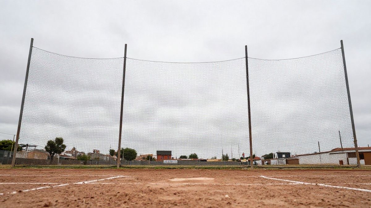 Illustrative image: low angle of a baseball net against a cloudy sky in a generic field