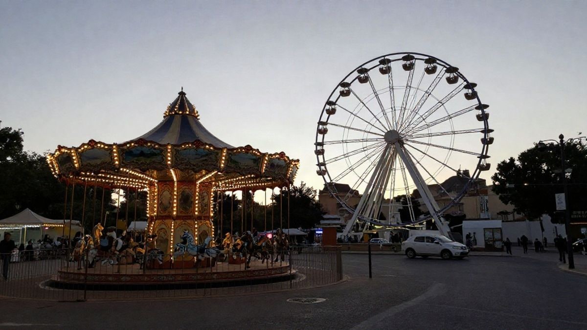 Imagen ilustrativa: carrusel y noria en un recinto ferial al atardecer