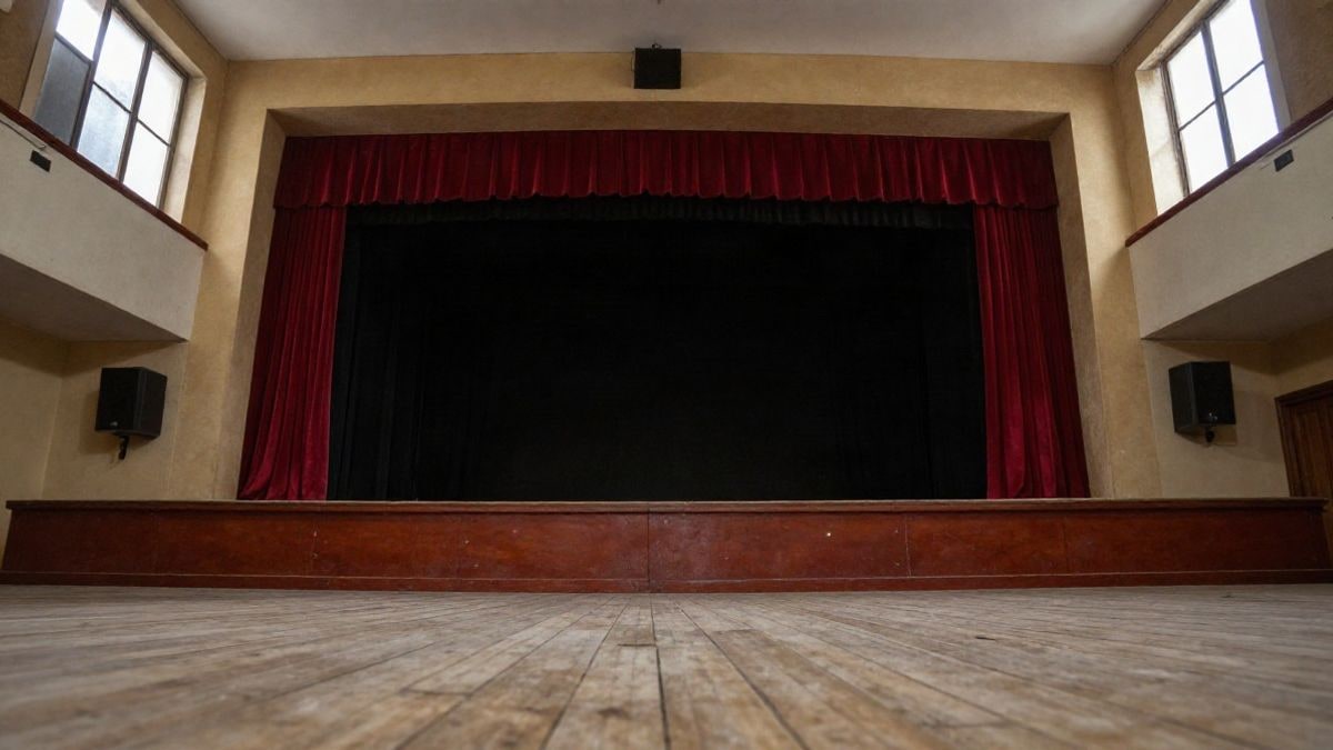 Imagen ilustrativa: escenario vacío de un teatro con cortinas rojas y suelo de madera