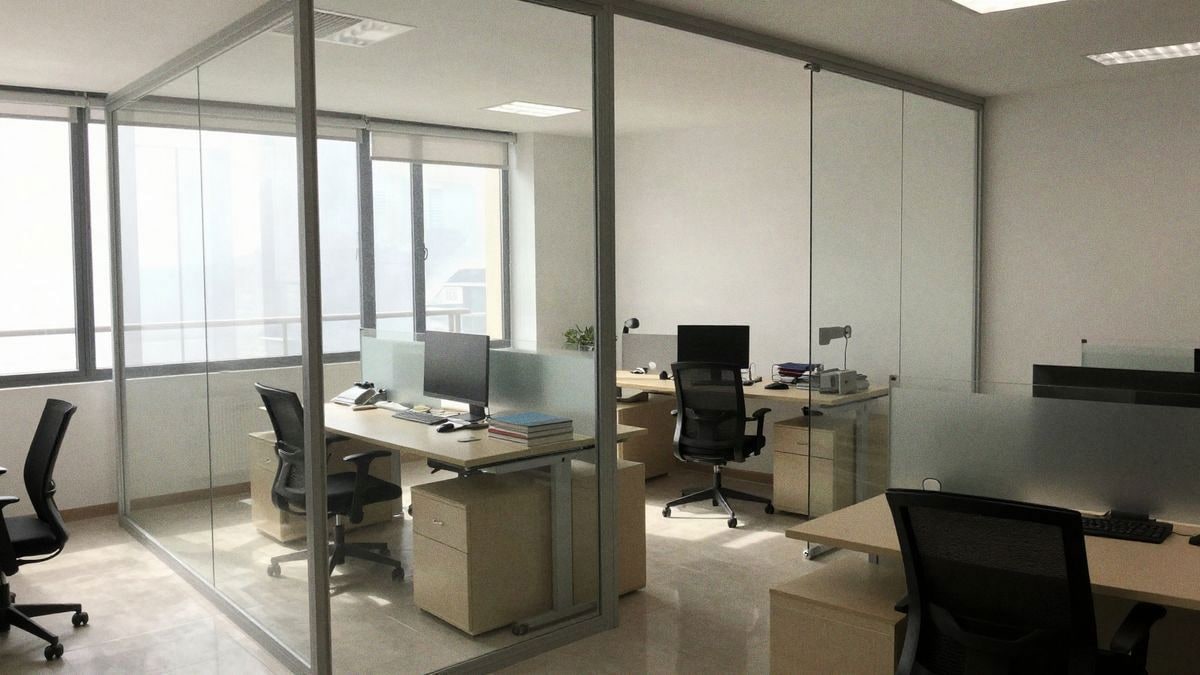 Office interior with glass partitions, natural light, modern furniture, and a clean, bright atmosphere.